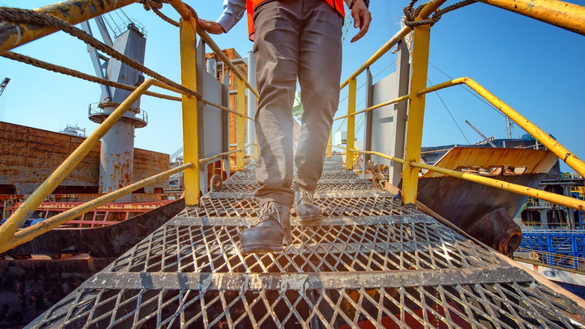 Walk at high legs of worker or engineering wearing Safety shoes walking in mind step on the steel gangway bridge cross over at workplace, working in high stage and high level of insurance"r